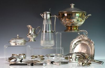 de nombreux objets en argent posés sur une table, sur fond gris