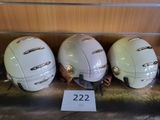 trois casques sont alignés sur une étagère à côté d'un panneau
