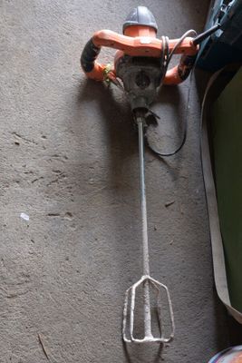 un batteur à main posé par terre à côté d'une paire de chaussures