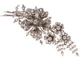 Une broche antique en forme de fleur sertie de diamants est présentée sur un fond blanc.