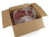 une boîte en carton contenant de la viande, posée sur une surface blanche