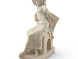 une statue représentant une femme assise sur une chaise