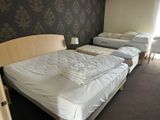 three beds in a room with a wallpapered wall behind them