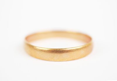 a close up of a gold wedding ring on a white surface