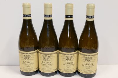 quatre bouteilles de vin blanc sont alignées sur une table