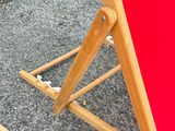 a red beach chair that is sitting on the pavement