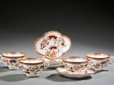 quatre tasses et soucoupes sont posées sur une surface grise