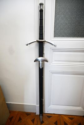 une épée posée par terre devant une porte