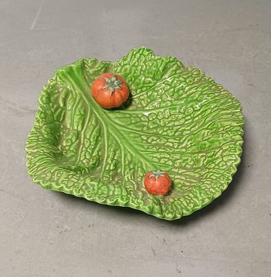 deux tomates posées sur un plat en forme de feuille, sur une table