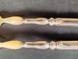two silverware spoons with yellow handles on a black surface