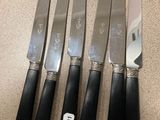 quatre couteaux sont alignés sur un comptoir, avec une étiquette de prix accrochée dessus