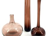 three glass vases sitting next to each other on a white surface