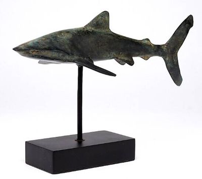 statue d'un requin posée sur un socle noir, sur fond blanc