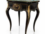 une table noire et dorée avec un plateau en verre posée sur un socle blanc