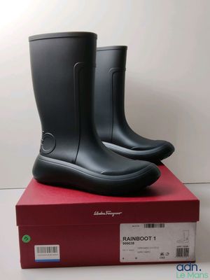 une paire de bottes de pluie noires posée sur une boîte rouge