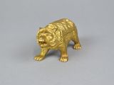 a gold figurine of a tiger on a gray surface