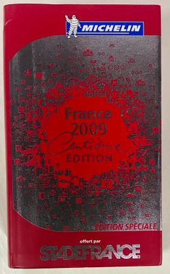 un gros plan d'un livre posé sur une surface blanche, avec une couverture rouge