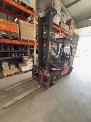 un chariot élévateur dans un entrepôt, avec des cartons sur les rayonnages
