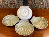three seashells sitting on a table with a clock in the background