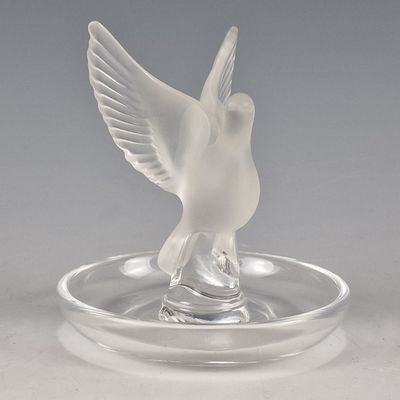 un oiseau en verre posé sur une assiette en verre