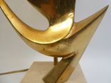 une sculpture en or représentant un oiseau, posée sur un socle en marbre