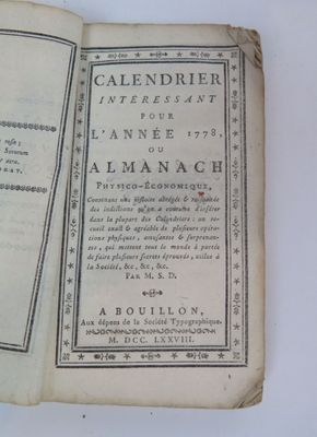 an old book with a black and white cover on a white table