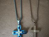 two cross pendants on a leather surface