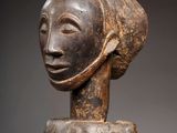 une sculpture en bois représentant une femme coiffée d'une coiffe