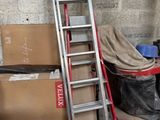 une échelle appuyée contre un mur, à côté d'une pile de cartons