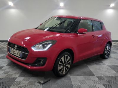 une Suzuki Swift rouge garée dans une pièce au sol à carreaux