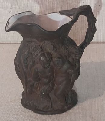 un petit vase marron muni d'une anse, posé sur une table