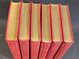 six red books stacked on top of each other on a table