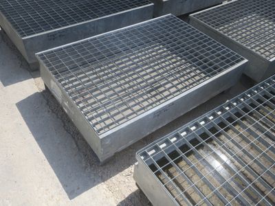 Plusieurs grilles en acier sont empilées les unes sur les autres au sol