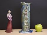 two figurines sitting on a table next to a green apple