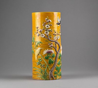 un vase jaune sur lequel sont peints des fleurs et des oiseaux