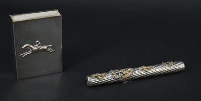 un stylo argenté et un livre posés sur une surface noire