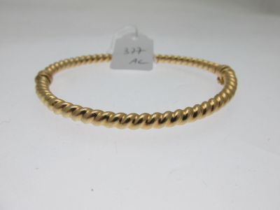 gros plan d'un bracelet en or sur une surface blanche