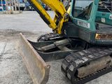 a green and yellow excavator sitting in a parking lot
