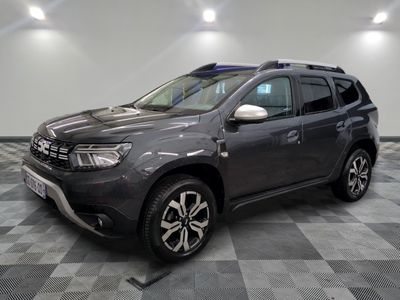 La Dacia grise est garée dans le garage, sur un sol à damier.