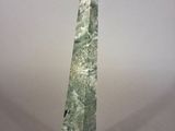 a close up of a green stone obelisk on a white surface