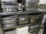 several pans are stacked on a metal shelf in a kitchen