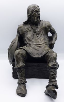 a bronze statue of a man sitting on a chair