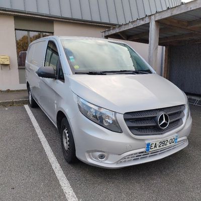 une camionnette argentée garée sur un parking à côté d'un immeuble