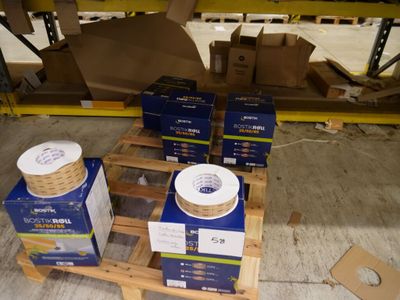 Des cartons de câbles électriques sont empilés sur une palette dans un entrepôt