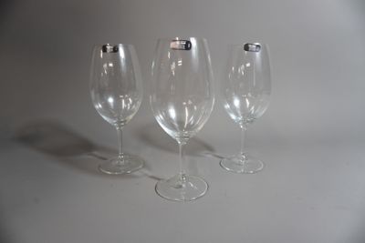 trois verres à vin vides posés sur une surface blanche