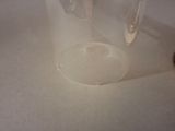 a glass jar with a small amount of liquid inside of it