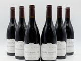 six bouteilles de vin sont alignées sur une surface blanche