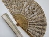 an image of a gold fan and ruler on a white surface