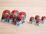 a set of four red casteors sitting on top of a wooden floor