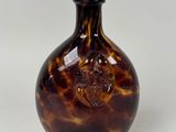 une bouteille en verre marron et noir ornée d'un crâne